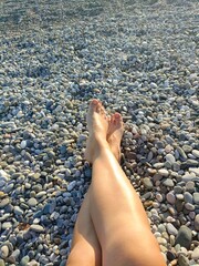 Person's bare feet resting with a relaxed mood representing a summer vacation against a stone beach background