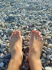 Woman's bare feet with a relaxed mood resting on smooth pebbles representing a spa treatment and...