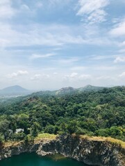 A scenic view of lush green mountains with an industrial zone nestled at the base, blending nature’s beauty with human development