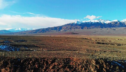 a view of the sand desert with snow-capped mountain peaks in the background