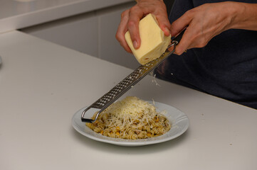 Woman Grating Cheese Over Tuna Pasta Dish