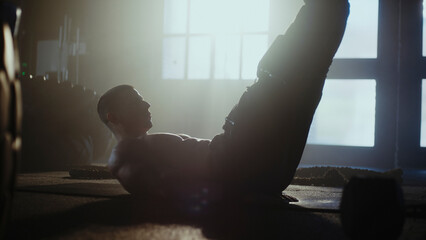 Determined athlete performing crunches in gym with dramatic lighting
