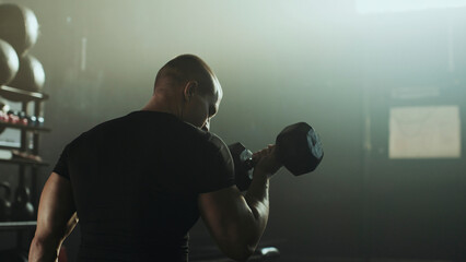 Determined bodybuilder lifting dumbbell during intense workout session