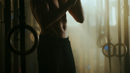 Muscular athlete preparing for gymnastics rings exercise in gym