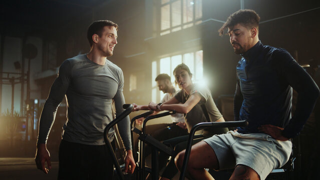 Fitness instructor coaching athletes using air bikes in cross training gym