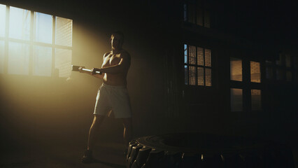 Athlete using hammer to hit tire in gym during workout