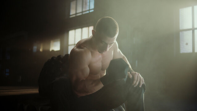 Muscular athlete resting after intense dumbbell workout in gym