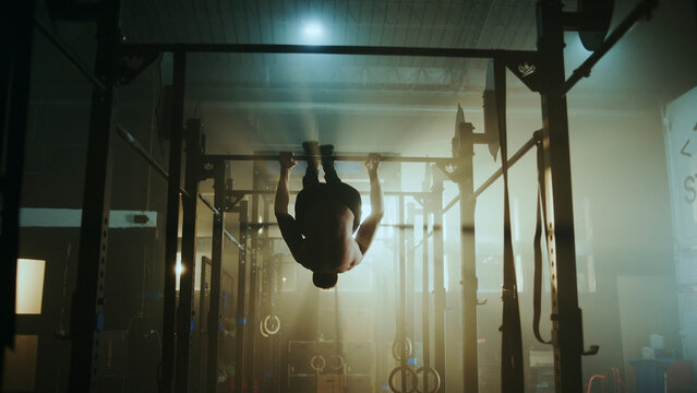 Determined athlete performing hanging leg raises in gym