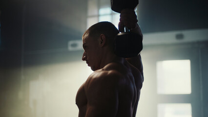 Determined bodybuilder lifting heavy dumbbell in gym