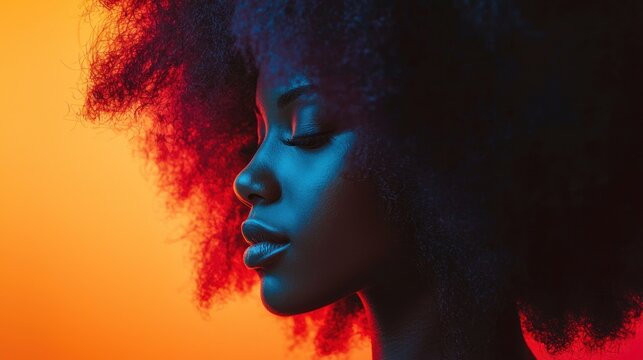A woman with curly hair, wearing a black top, standing in front of a vibrant orange background with a gradient effect.