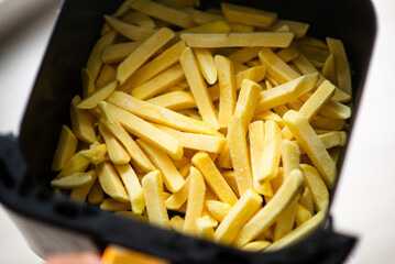 Frozen french fries in air fryer basket perfect for quick cooking.