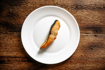 Grilled salmon on white plate with rustic wooden background.