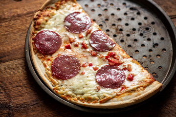 Half-eaten pepperoni pizza on rustic wooden table.