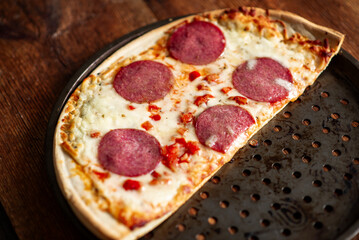 Hot pepperoni pizza on rustic wooden table with crispy crust and melted cheese.
