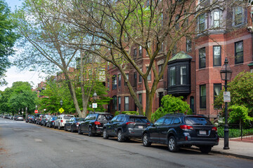 Obraz premium Quiet residential street lined with parked cars and historic red-brick townhouses in Boston, Massachusetts, USA