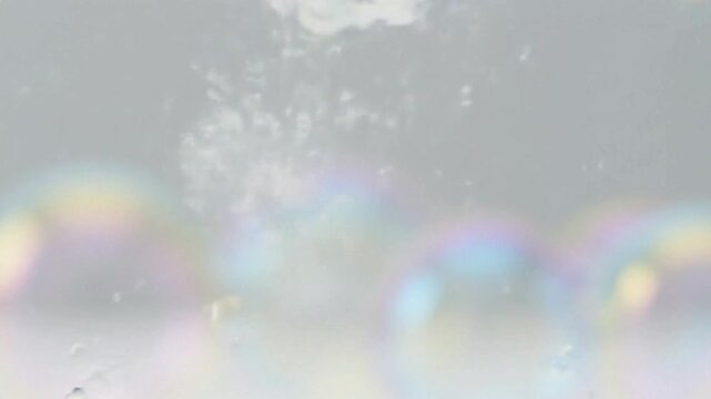 Opaque white bubbles some with faint iridescent rainbows against a cloudy gray backdrop