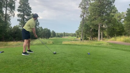 A man teeing off with a driver during golden hour on a beautiful golf course.
