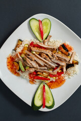 A plate of hearty beef stir-fry, complete with vibrant slices of vegetables, atop a bed of steamed white rice