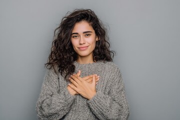 Heartfelt thanks Grateful young Latin woman clasps hands on her chest expressing genuine appreciation for kindness