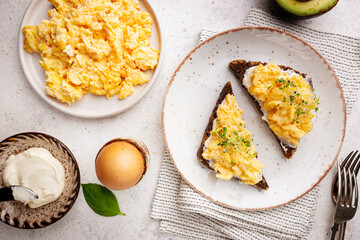Scrambled egg sandwich with cream cheese on rye toast for breakfast on white background, top view. Healthy breakfast or snack