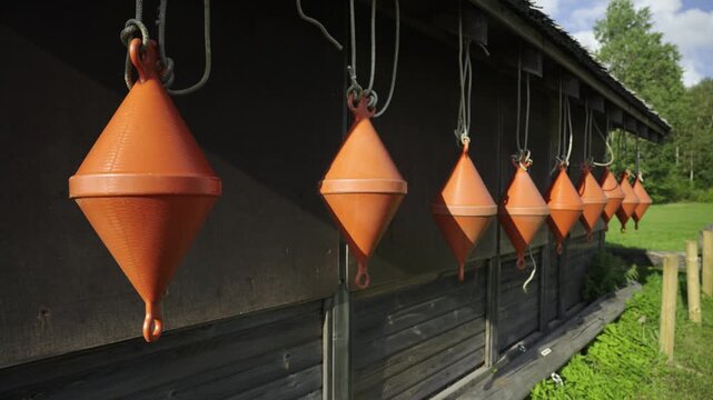Orange floats suspended from the roof of a wooden house. The shore of the Baltic Sea on a sunny day. floats for fishing serts. Latvia
