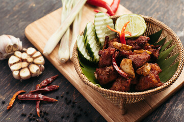 Spicy Dark Brown Meat Dish with Chili, Lime, and Lemongrass Garnish