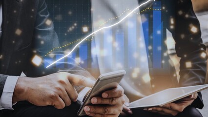 Business professionals engage with technology and analyze financial data trends using smartphones and tablets in a modern office environment. Copula