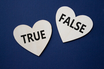 True or False symbol. Concept word True or False on wooden hearts. Beautiful deep blue background....