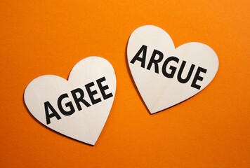 Agree or Argue symbol. Concept word Agree or Argue on wooden hearts. Beautiful orange background....