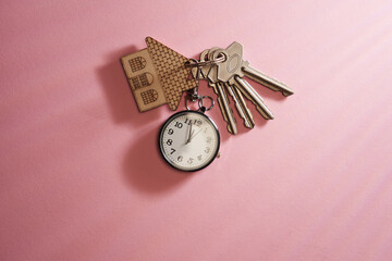 house shaped key ring and clock against pink background
