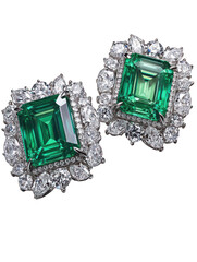 Emerald and diamond stud earrings, close-up.  Two square-cut emerald gemstones, nestled in a halo of smaller diamonds, are showcased against a black background.  Detailed filigree design