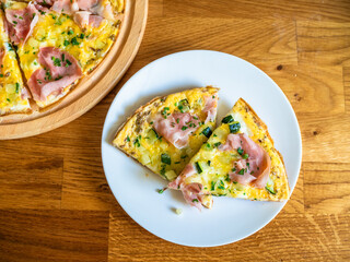 Frittata - scrambled eggs with zucchini and boiled ham on wooden table	