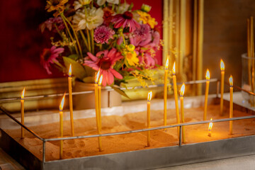 Religious altar with a crucifix framed in gold against a red backdrop, surrounded by lit candles...