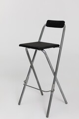 This is a modern folding bar stool designed with a comfortable black cushioned seat