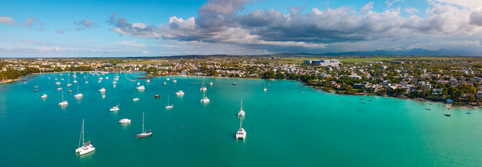 Aerial panorama of Grand Baie Mauritius with turquoise lagoon anchored catamarans and town...