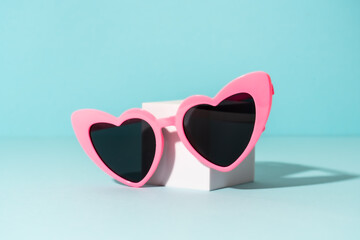 Sunglasses on white podium with sunny shadows.