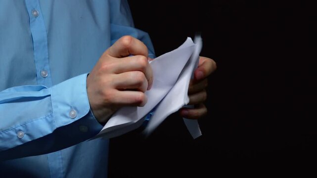 An angry office worker tears up a piece of paper in the office.
Anger and emotions in the office.
Conflict at work and problems with signing a contract.
A man tears up a contract