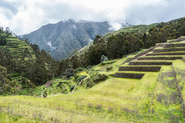 Ancient Inca stone terraces at the archaeological site of Chinchero, Peru against misty Andean...