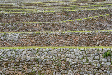 Ancient Inca stone terraces at the archaeological site of Chinchero, Peru against misty Andean mountains