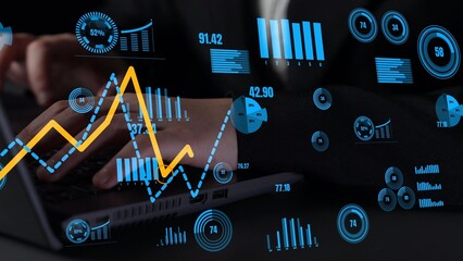 A business professional engages with a laptop displaying dynamic financial graphs and data analysis overlays, reflecting modern analytics in the workplace. Xenic
