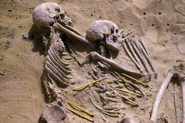 Skeleton sculpture partially buried in sand outdoors