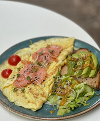 Omelette with Red Fish and Avocado on Bread on a Blue Plate

