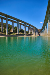 Tranquil scenery under a bridge over a reservoir with crystal clear turquoise water.