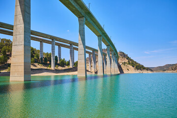 Tranquil scenery under a bridge over a reservoir with crystal clear turquoise water.