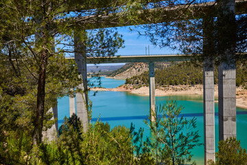 Tranquil scenery under a bridge over a reservoir with crystal clear turquoise water.