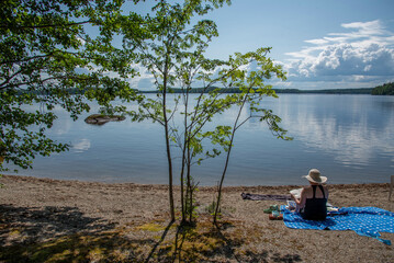 Woman sitting on the beach at Lake Saimaa in Finland