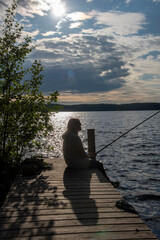 Woman fishing on the pier at evening