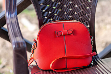 This is an image of a red handbag with a bow on the front
