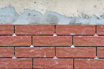 Fototapeta premium This image shows a close-up of a brick wall with a visible layer of mortar or cement between the bricks