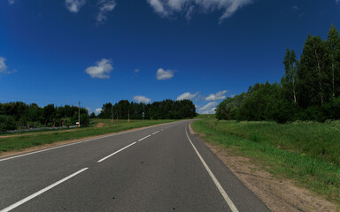 Fototapeta premium Road view on a summer day. Highways and bridge, roadside and white road line markings.